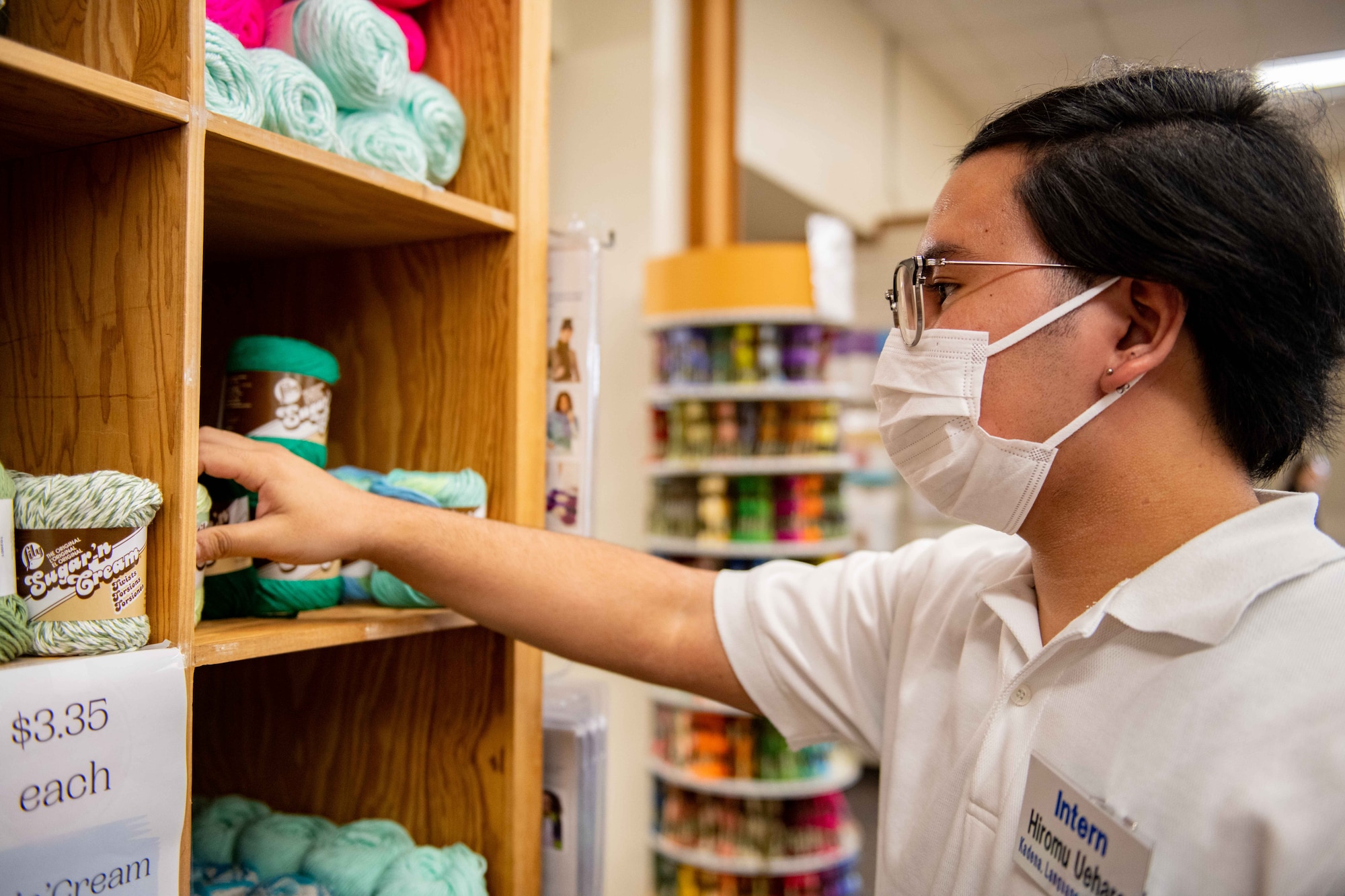 A Japanese boy organizes spools of yarn inside a cupboard