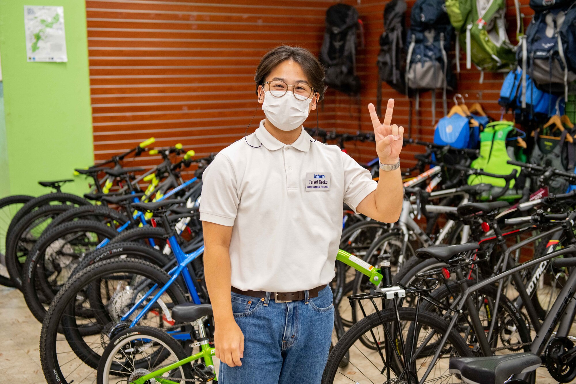 A Japanese boy poses in front of a bunch of rental bikes.