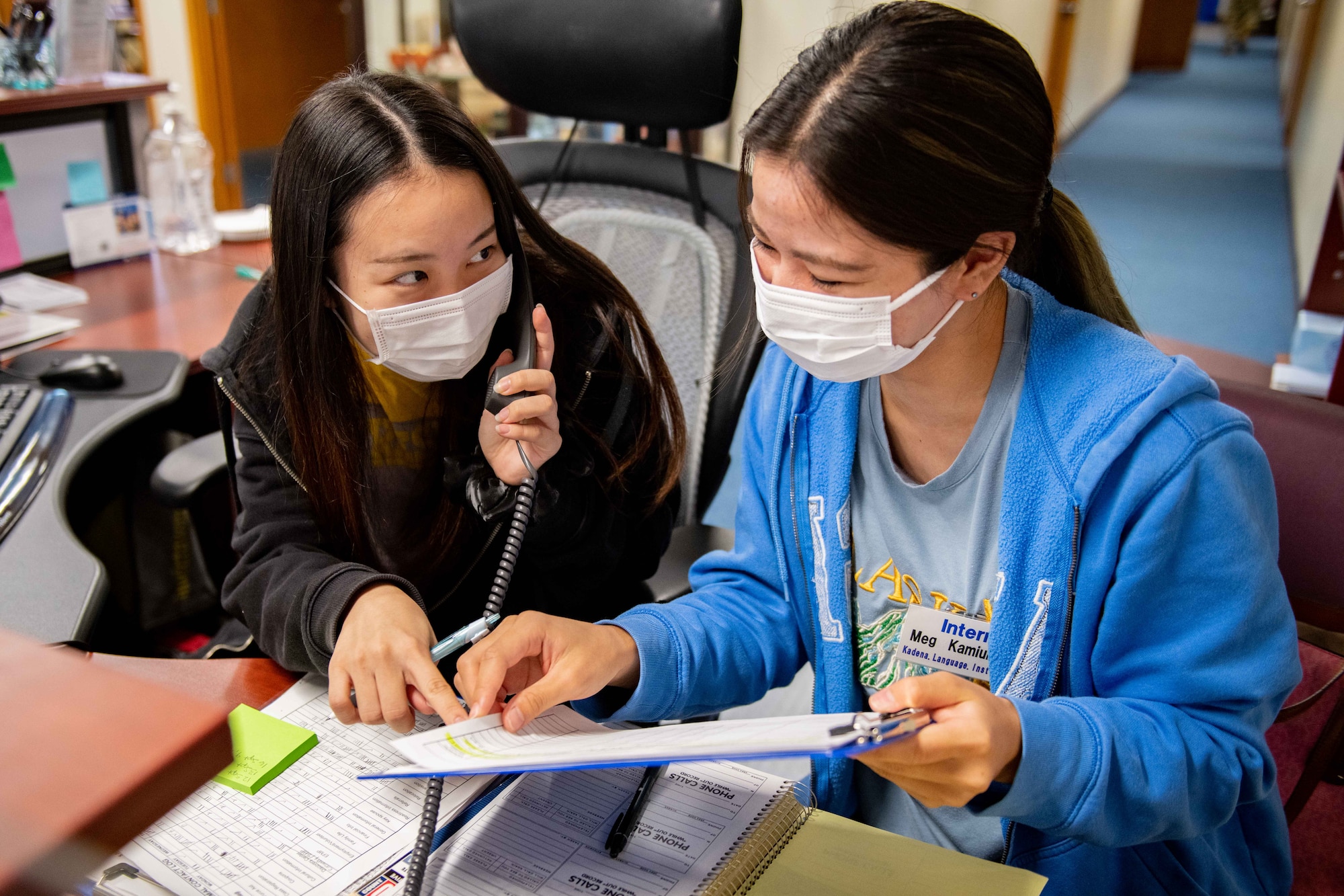 Two Japanese girls work together to solve a customers problem over the phone