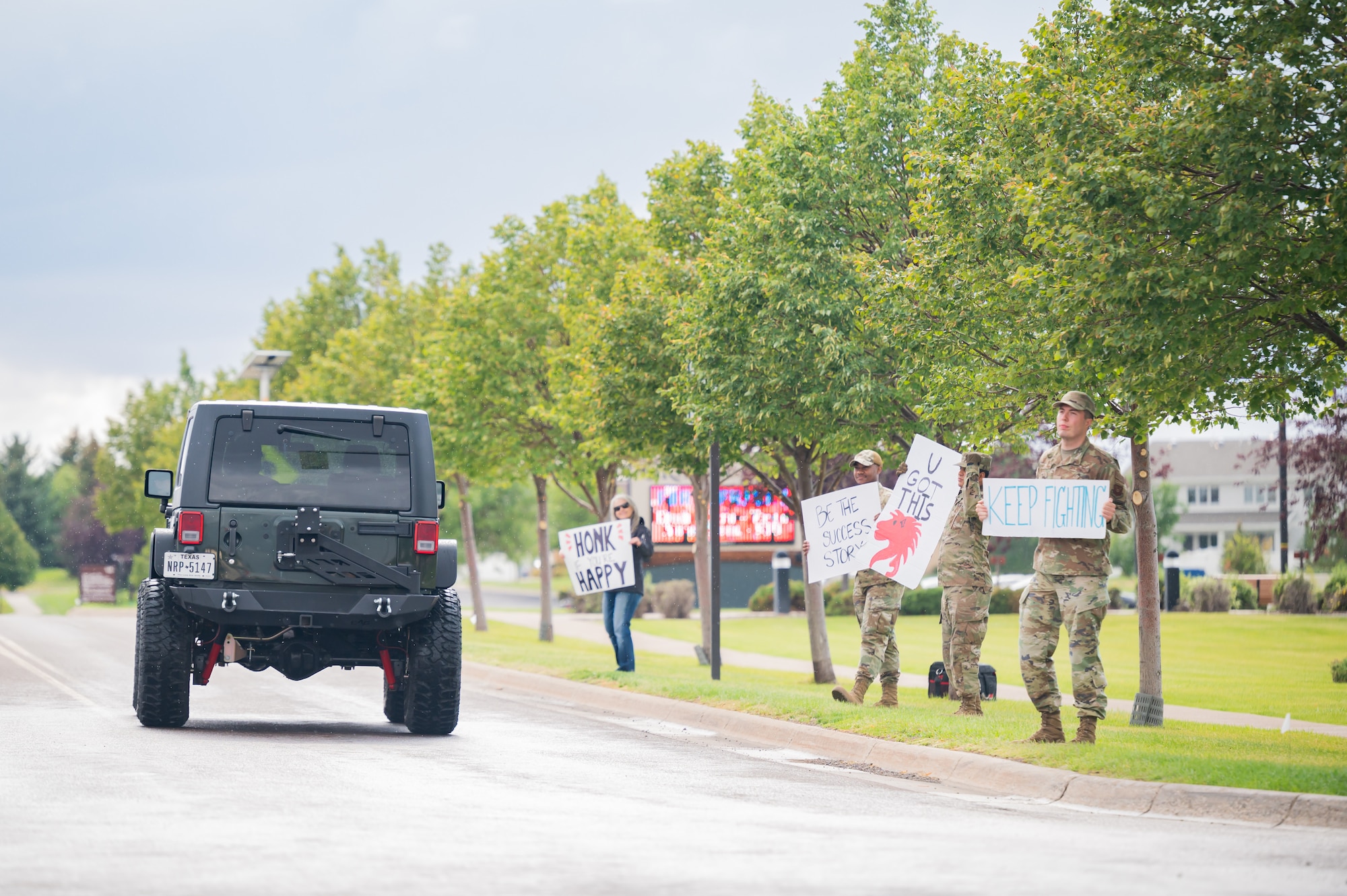 Airmen and family members hold signs of encouragement as people leave the installation Sept. 9, 2022, at Malmstrom Air Force Base, Mont.