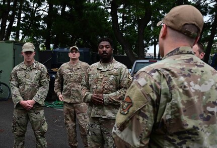 Group of service members listen as someone talks.