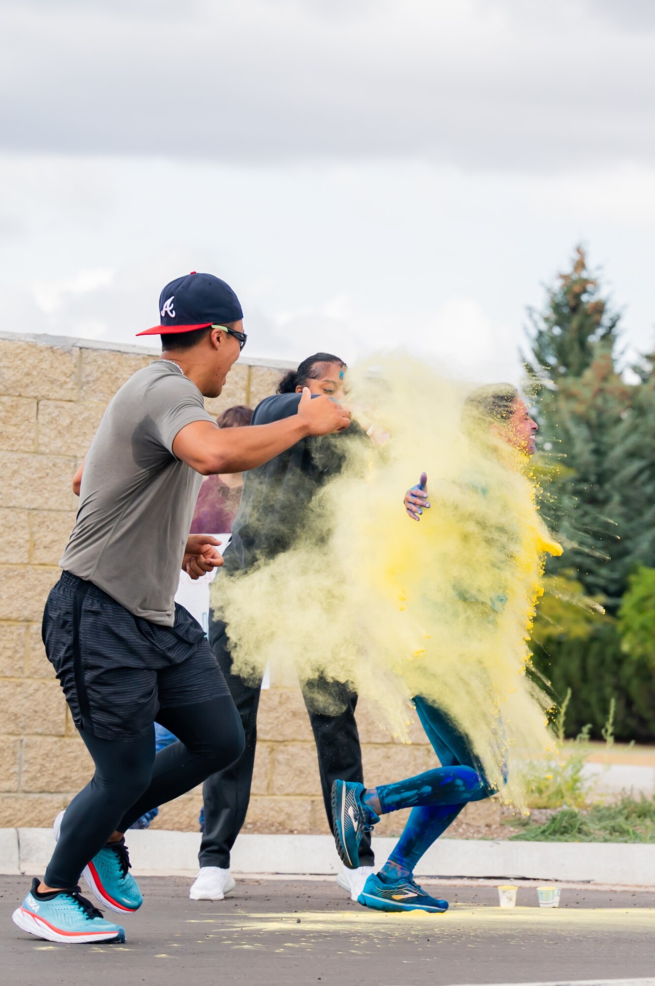 A person throws yellow paint at two other people while running.