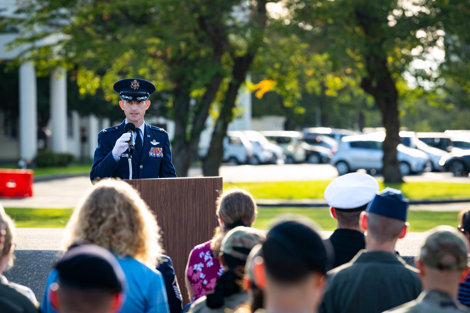 U.S. Air Force members in dress blues gives a speech at a podium.