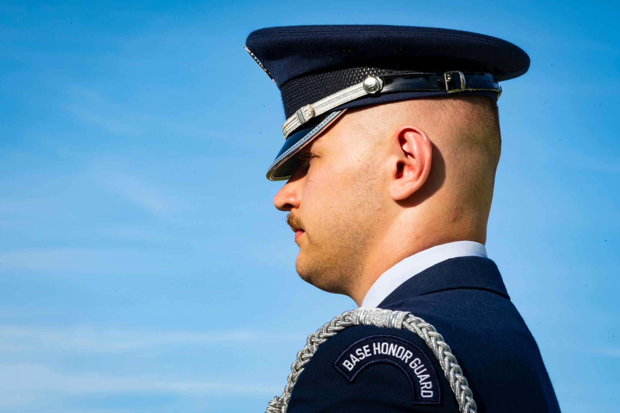 U.S. Air Force members in dress blues stands at attention with the sky in the background