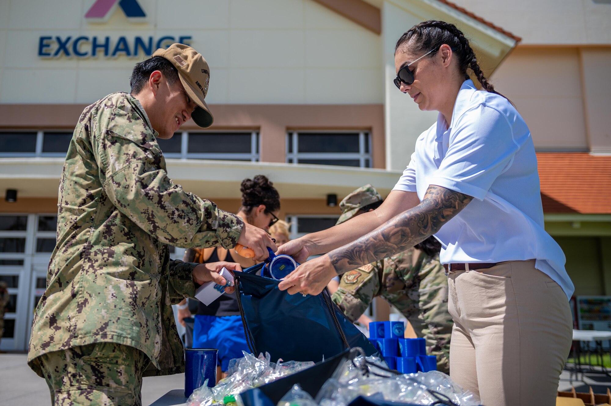 An Airman helps a service member place freebies inside of a bag
