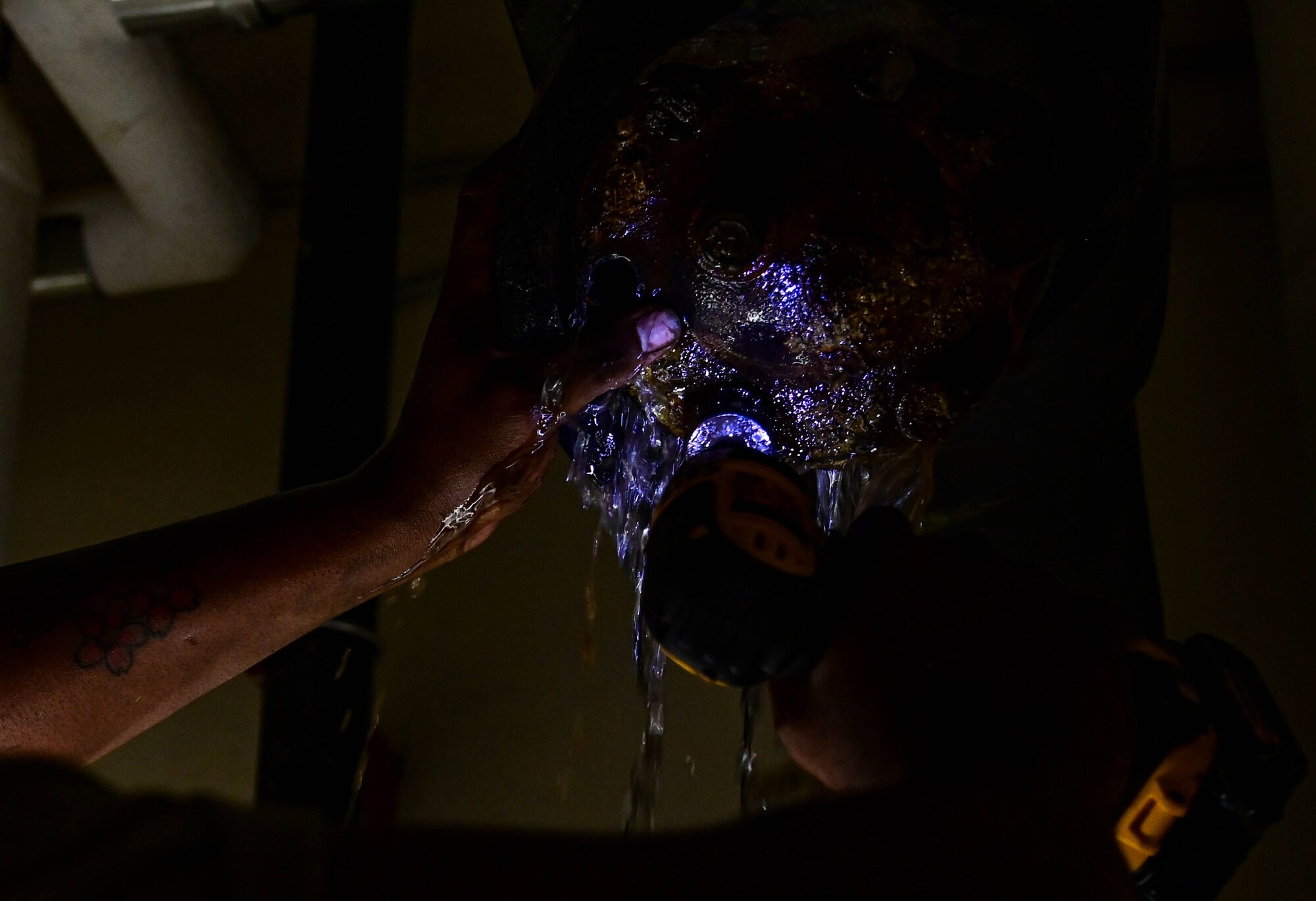 Water drips from a pipe, falling through someone's hands.