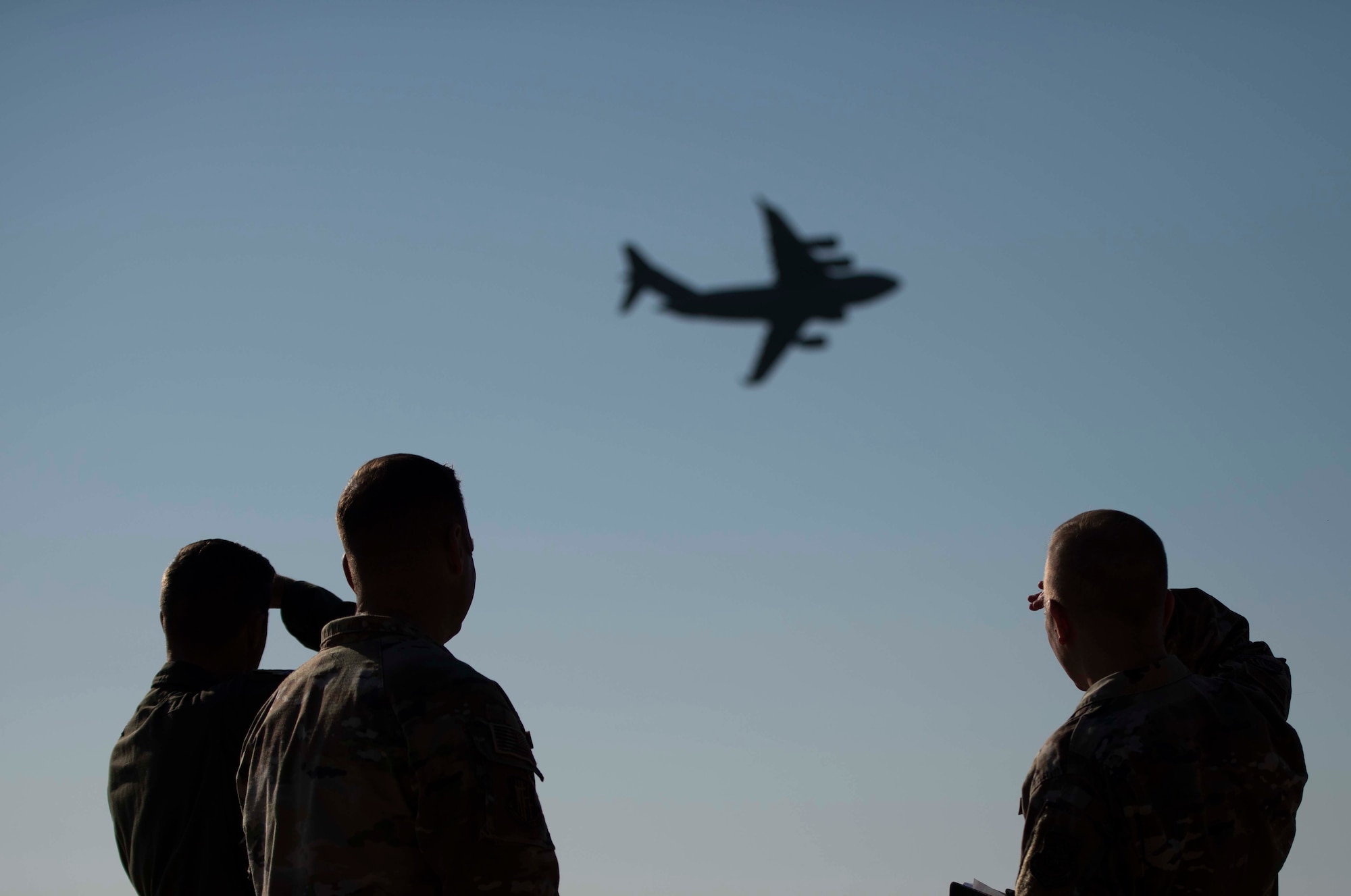 Airmen watch a plane fly over base.