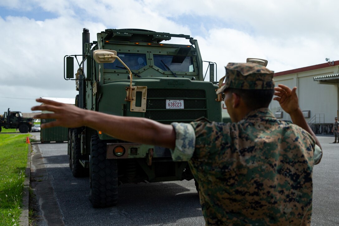 A U.S. Marine ground guides a Medium Tactical Vehicle Replacement with 3d Marine Division, transporting Marine Corps Utility Task Vehicles in support of an Alert Contingency Marine Air-Ground Task Force (ACM) drill at Marine Corps Air Station Futenma, Okinawa, Japan, Sept. 1, 2022.