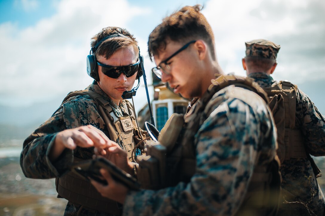 U.S. Marine Corps Cpl. Devin Mullin and Cpl. Alexander Rodriguez, both with 1st Battalion, 12th Marines, relay information through the Marine Air Ground Task Force Common Handheld during a joint terminal attack controllers training event at Marine Corps Base Hawaii, Sept. 6, 2022.