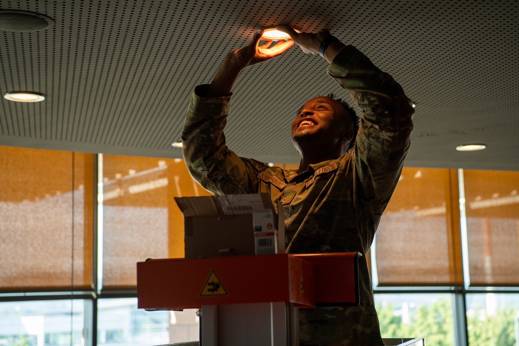 U.S. Air Force Senior Airman Tyreece Somma-Watkins, 786th Civil Engineering Squadron electrical systems technician, checks light fixtures at HEROES in the Kaiserslautern Military Community Center at Ramstein Air Base, Germany, Aug. 2, 2022.