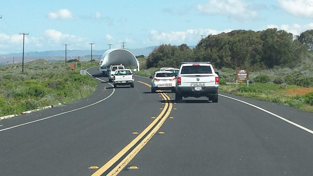 Trucks driving on the road bring up the rear of a convoy transporting equipment.