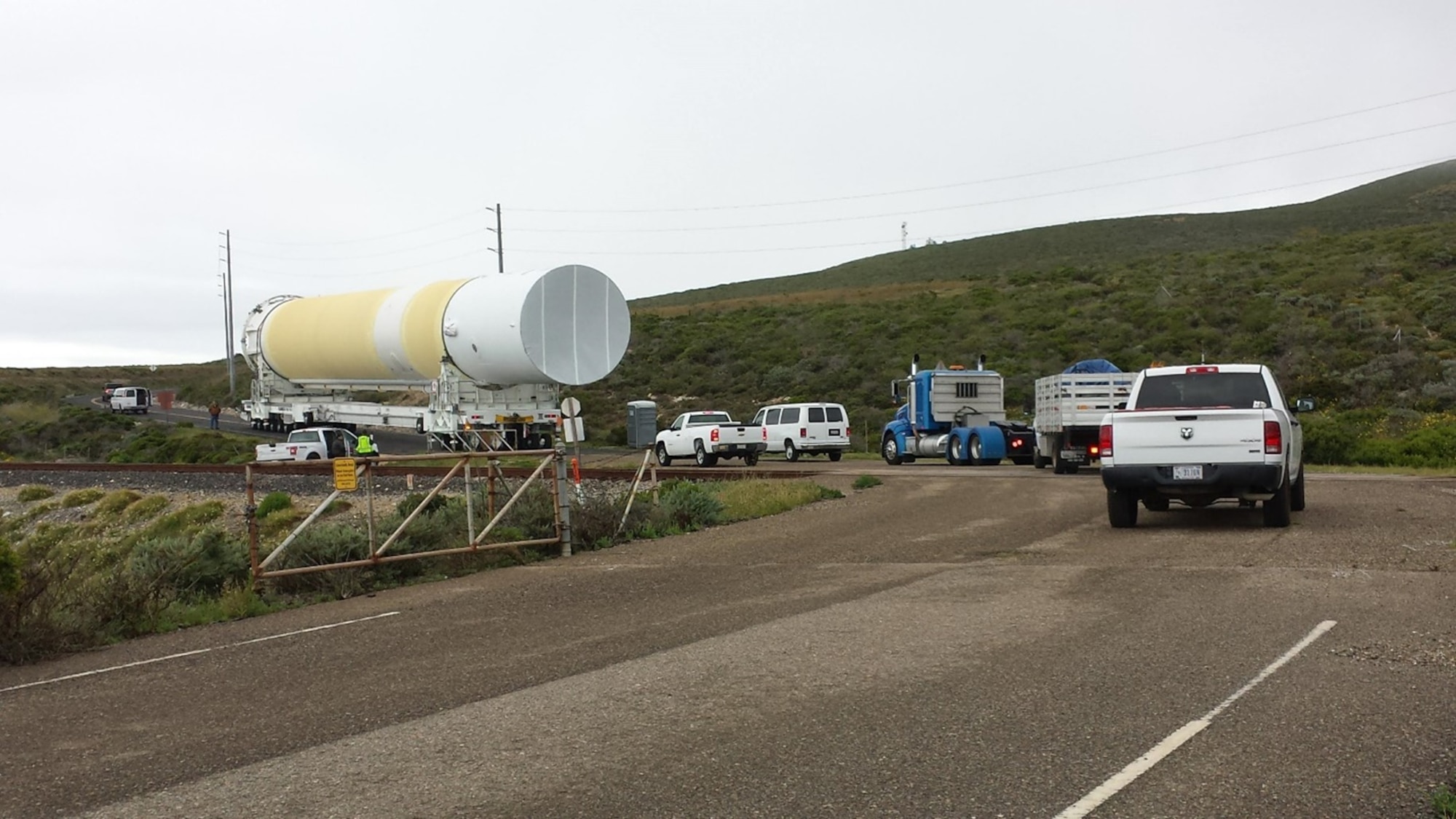 A convoy of trucks and vehicles guides a rocket booster down the road