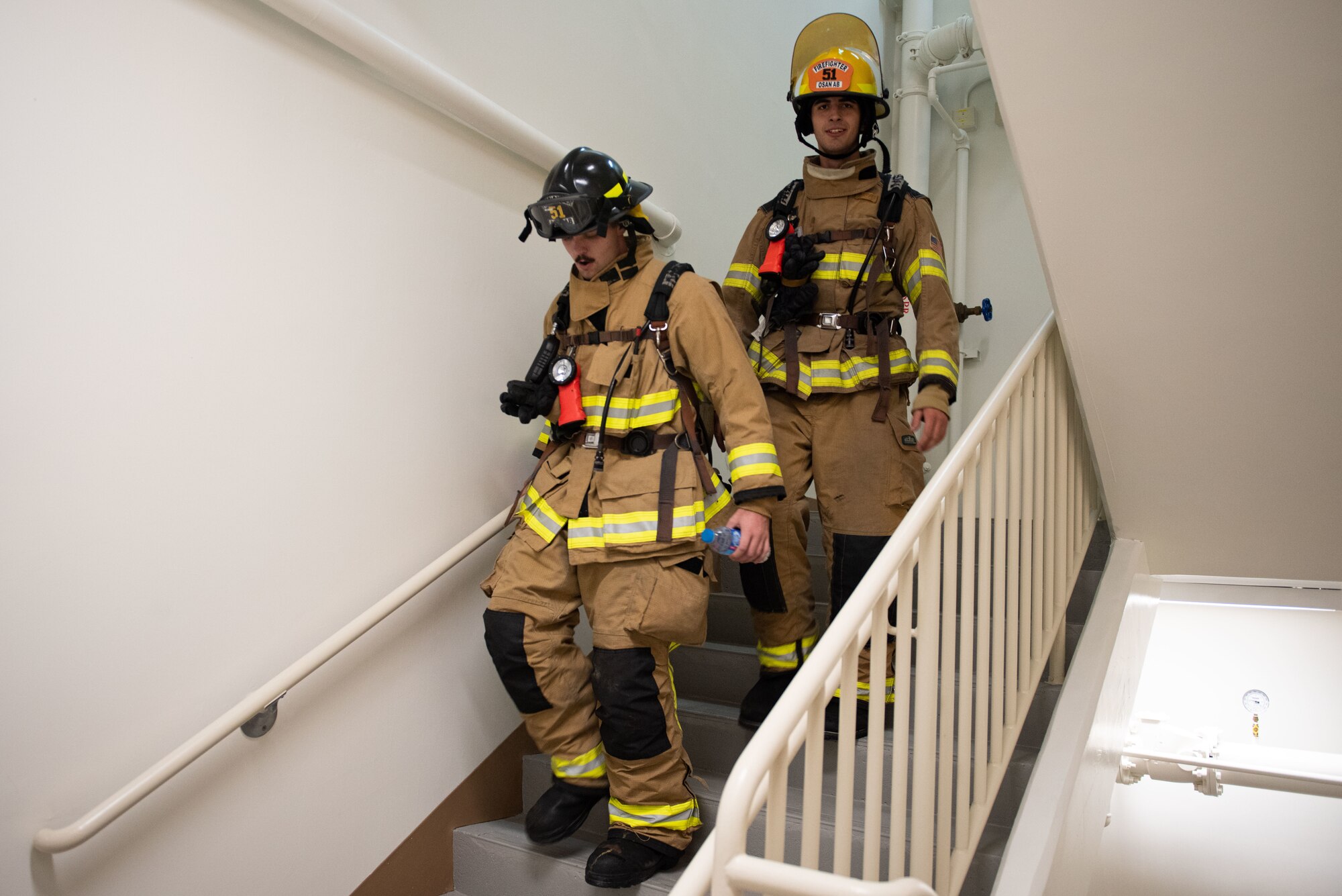 Airman 1st Class Brendan Casserly and Airman Noah Grantham, 51st Civil Engineer Squadron firefighters, descend a flight of stairs during the annual stair climb challenge as part of a 9/11 Remembrance Ceremony at Osan Air Base, Republic of Korea, Sept. 10, 2022.