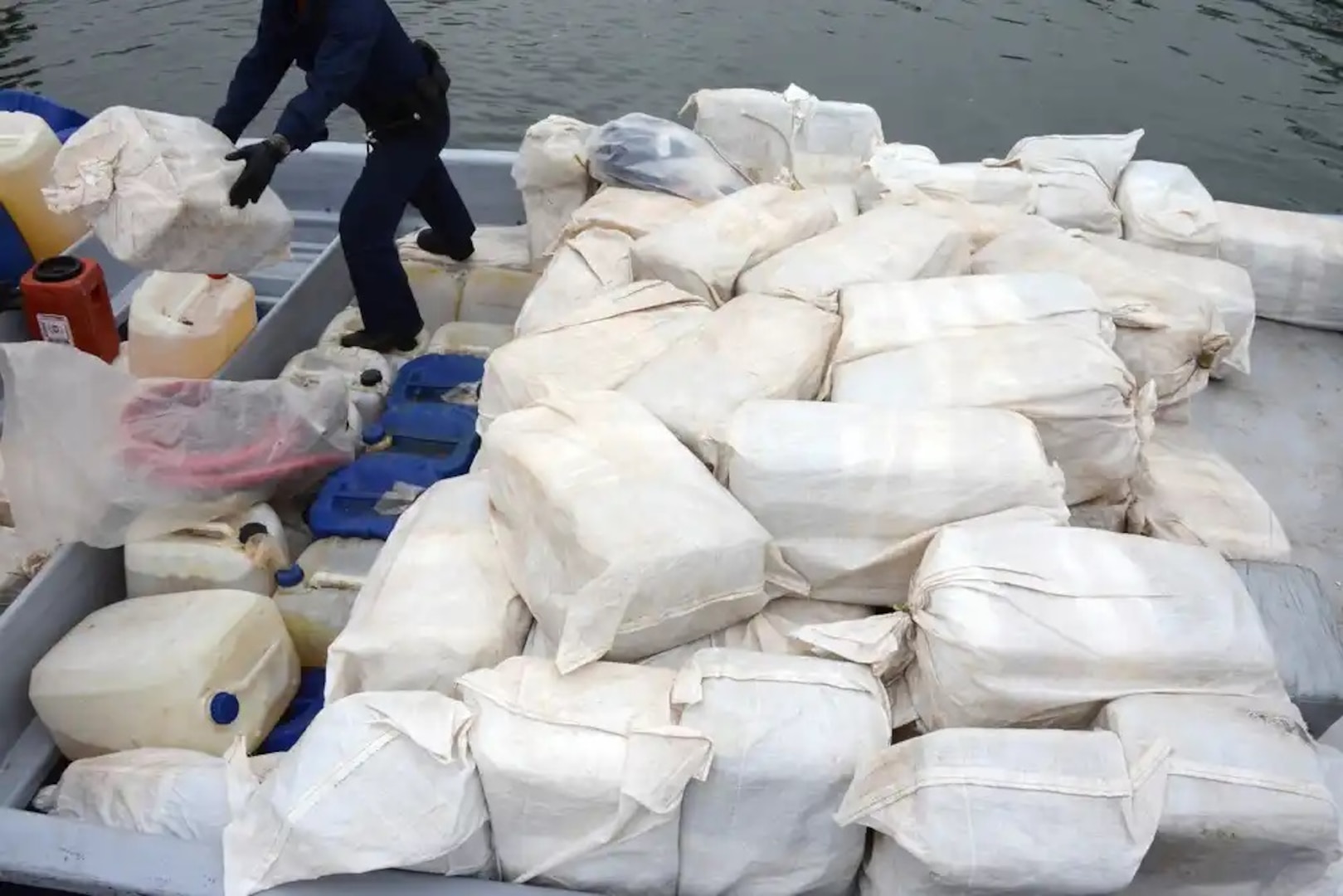 A U.S. Coast Guard crew member unloads a bale of marijuana from a panga boat that was seized 160 miles southwest of San Diego June 28, 2014. The Coast Guard detained three suspects and seized approximately 7,600 pounds of marijuana. (U.S. Coast Guard photo by Petty Officer 1st Class Henry G. Dunphy)