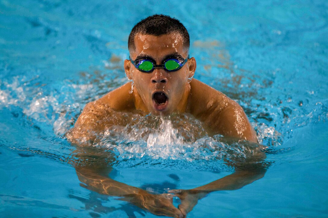 A Marine swims in a pool.