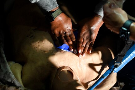 An airman covering an open wound on a medical mannequin.