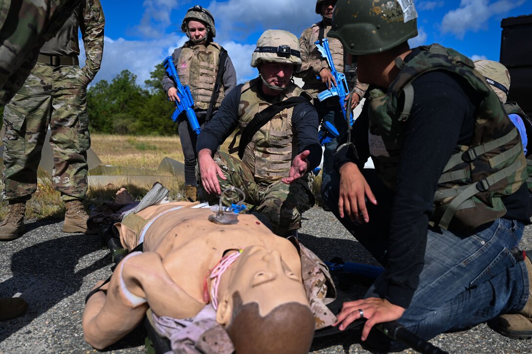 Airmen gathered around a medical mannequin.
