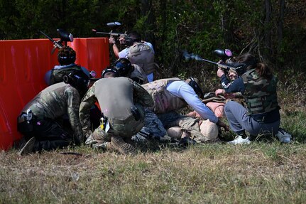 A group of Airmen fire paintball guns during an exercise.