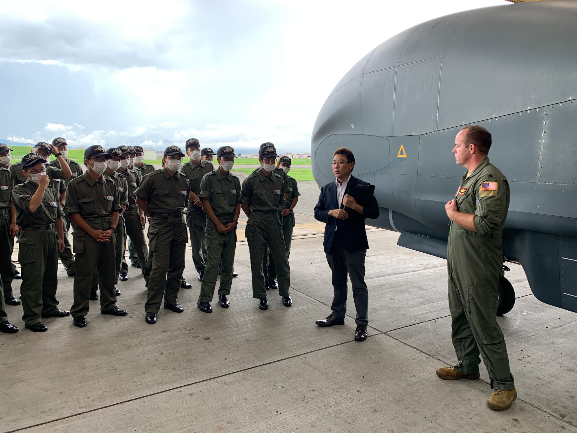 Hideaki Hirano, U.S. Forces Japan and 5th Air Force interpreter, and U.S. Air Force Lt. Col. Cory Turner, 9th Reconnaissance Squadron director of operations, speak to Japan National Defense Academy cadets next to a U.S. Air Force RQ-4 Global Hawk remotely piloted surveillance aircraft July 26, 2022, at Yokota Air Base, Japan. During the tour, cadets learned about the Global Hawk aircraft and several other American aircraft. (Courtesy photo)