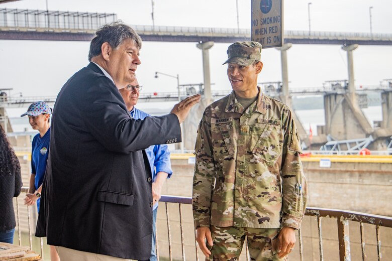 man in army uniform standing next to a man in a suit.