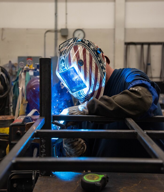 Naval Surface Warfare Center, Carderock Division employee welds metals together.