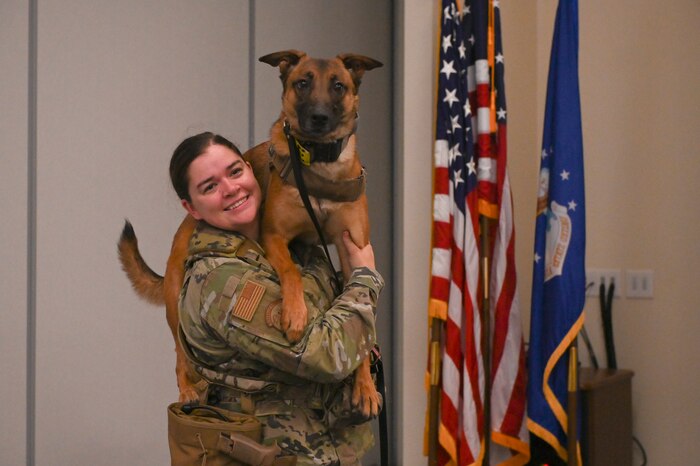 U.S. Air Force Senior Airman Kaitlynd Newland holds Military Working Dog Zzakira on her shoulders while smiling.