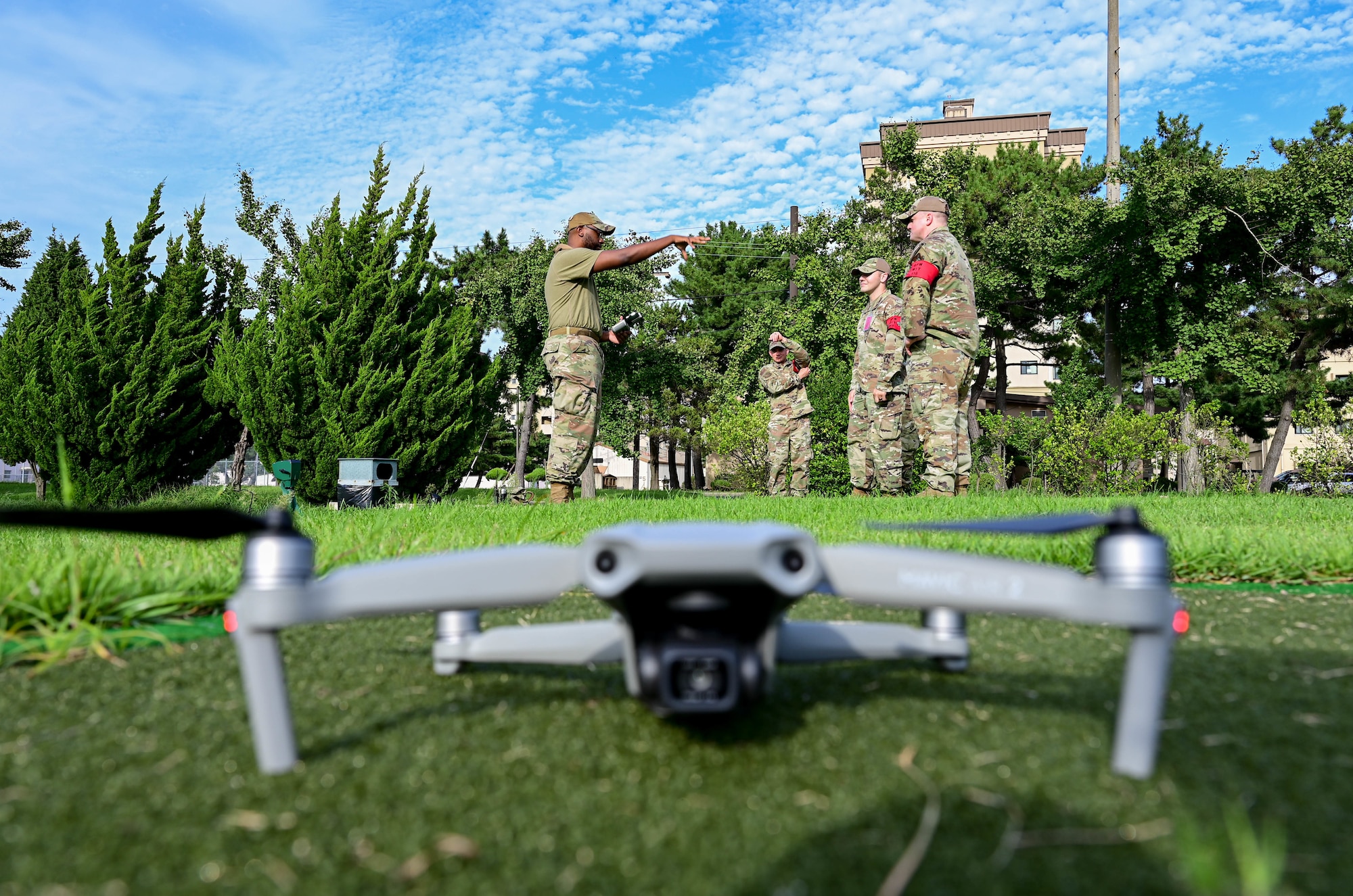 Drone rests on ground with military members standing behind it.