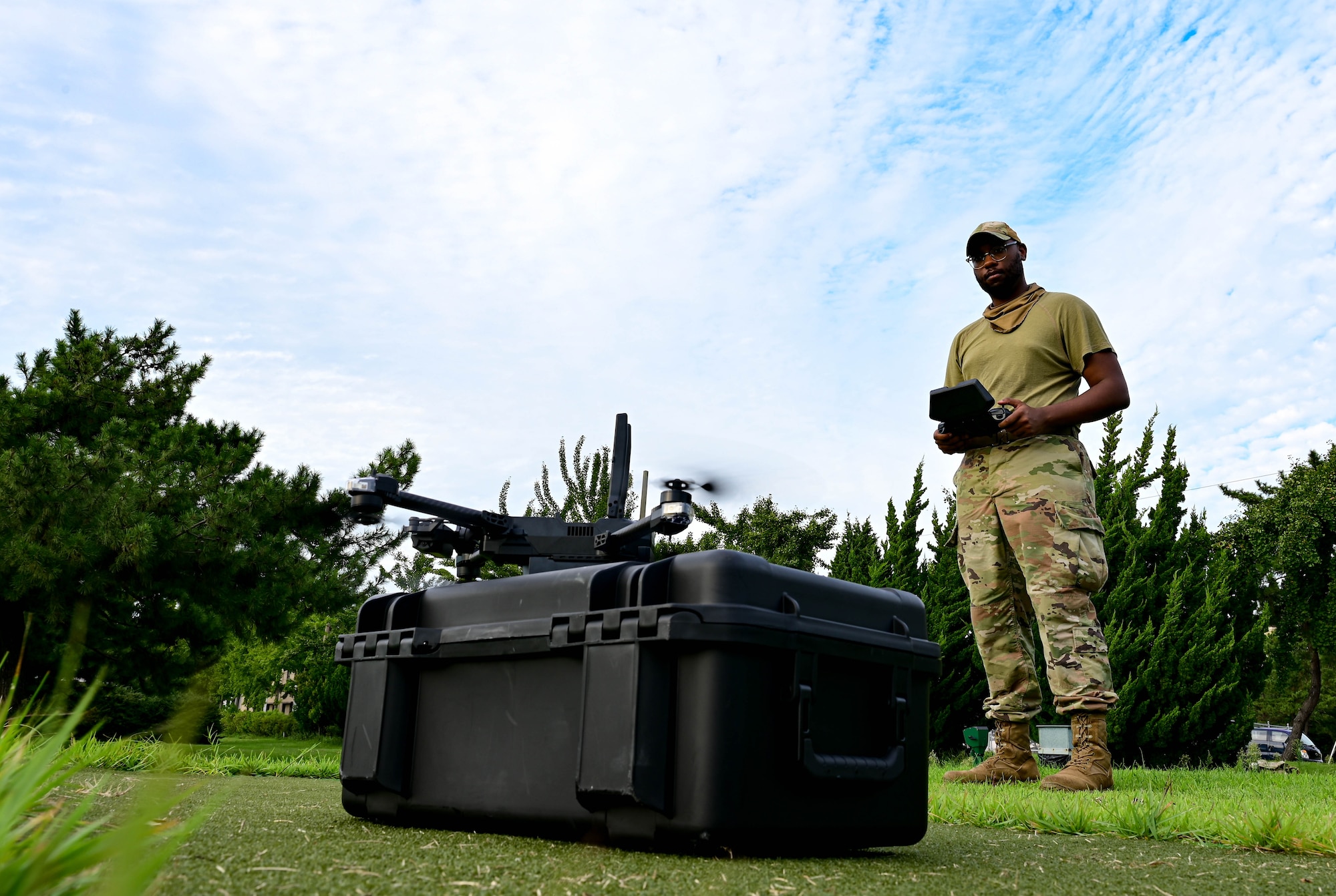 Man stands outside holding drone controller.