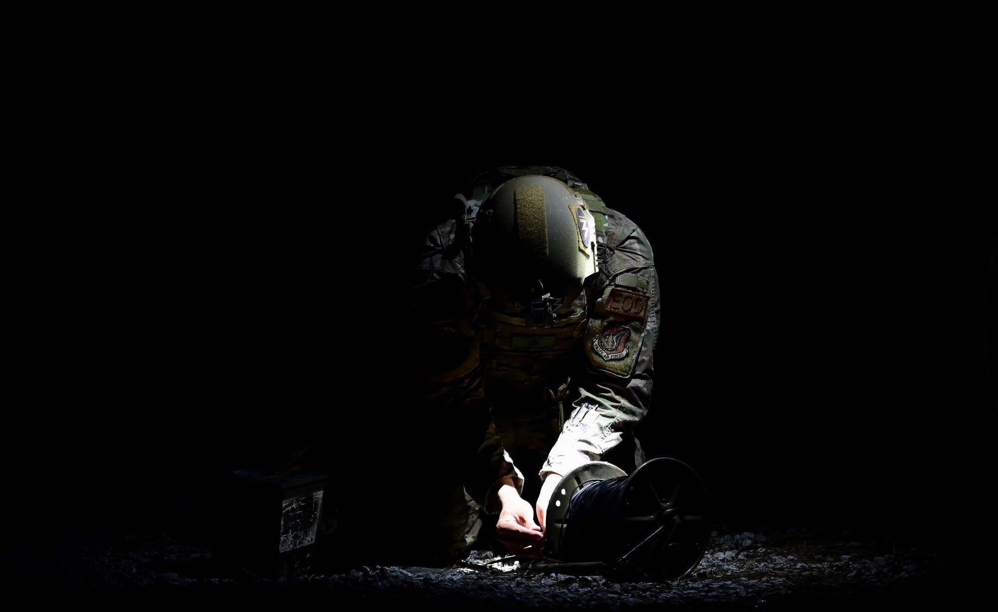 Man kneeling in dark sets up explosive.