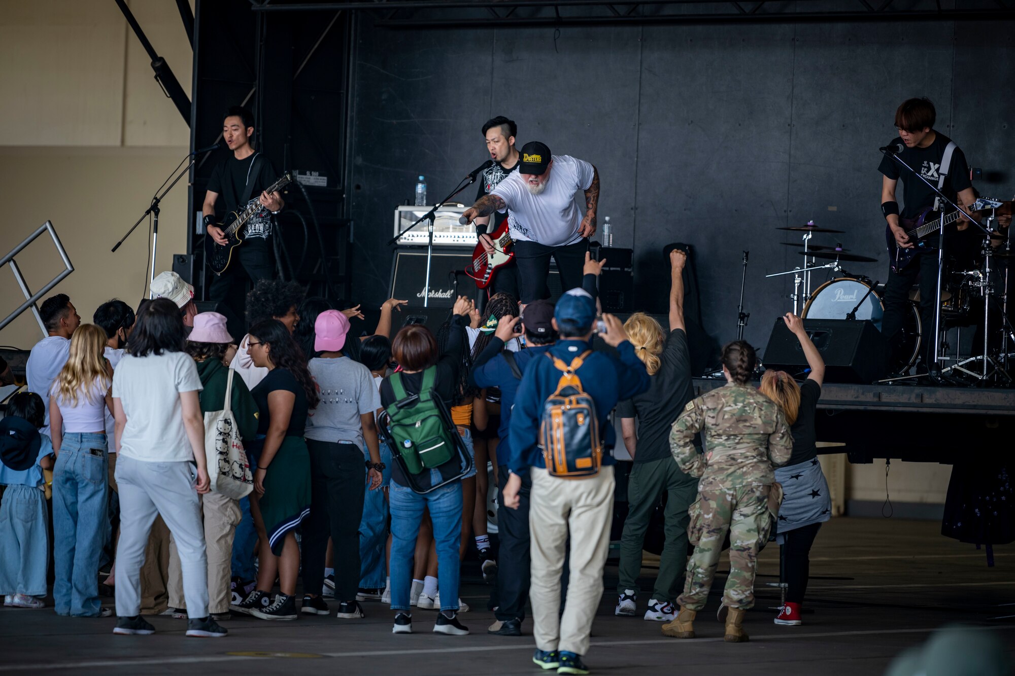 Band member on stage holds out microphone as the audience sings and dances.