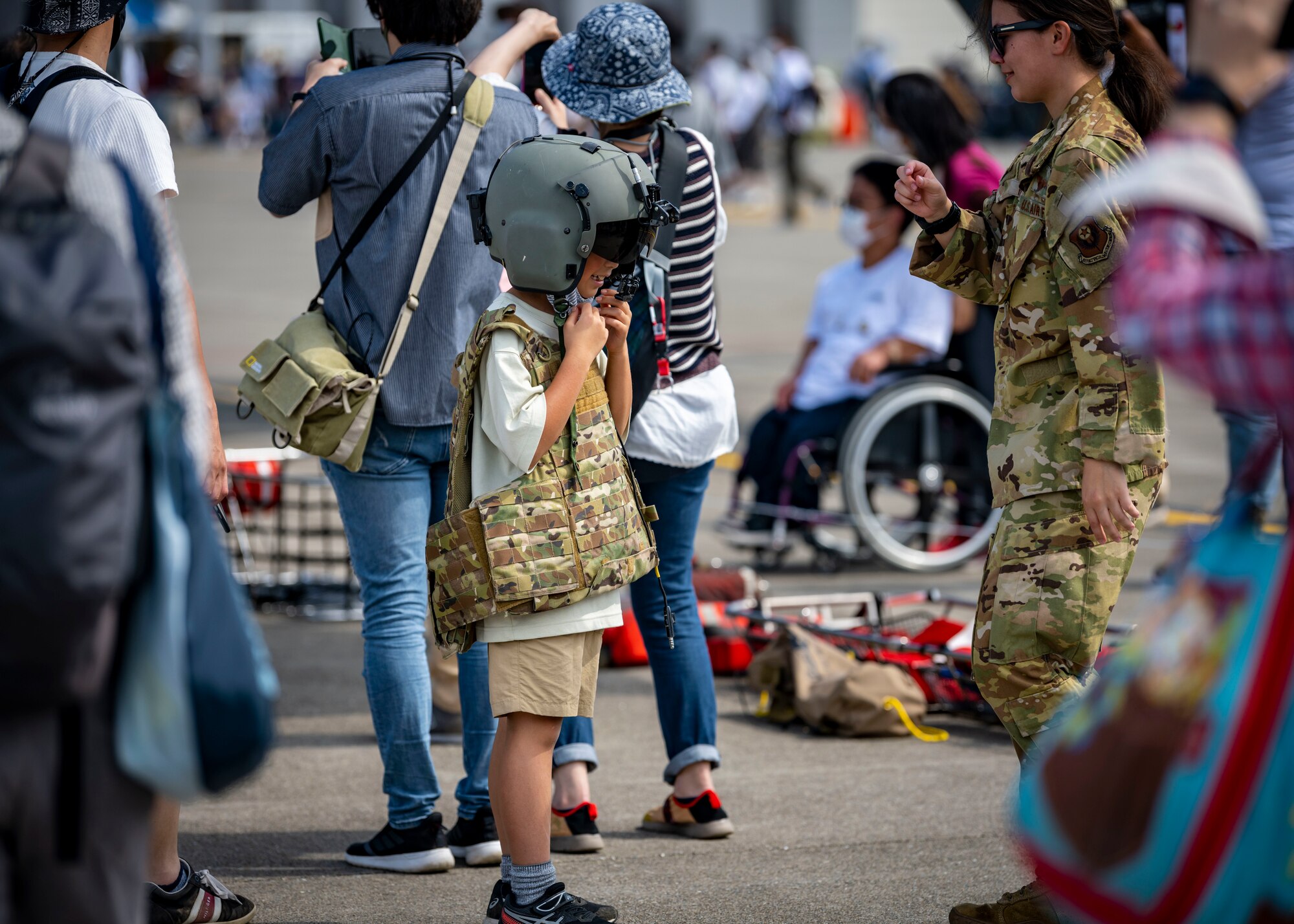 U.S. military member helps a Japanese child put on equipment.