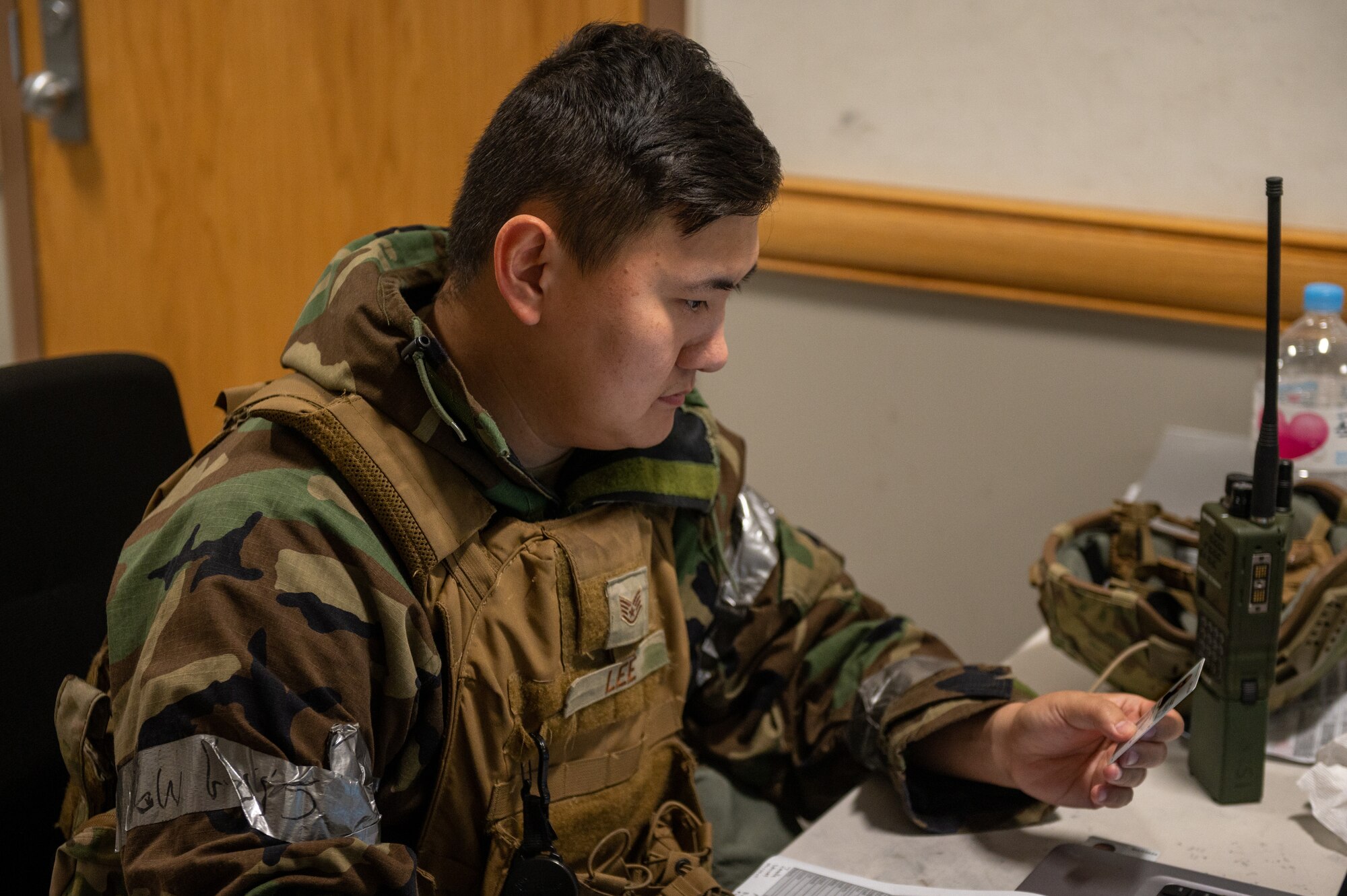 U.S. Air Force Staff Sgt. Sol Lee, 51st Security Forces Squadron (SFS) defender, verifies a military identification card during an augmentee recall as part of a base-wide training event