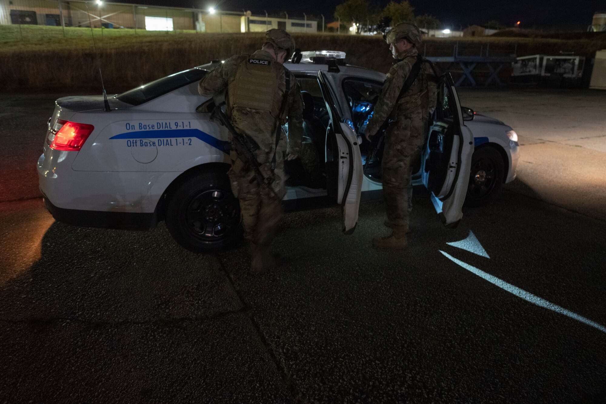 Airmen load a simulated suspect into a patrol car.