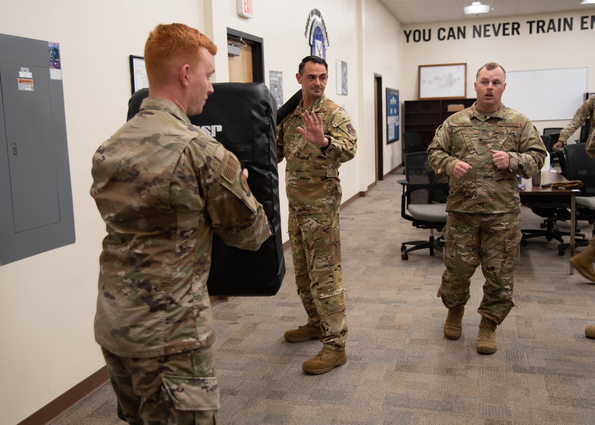 An Airman holds a padded shield across from Rubio who is in a fighting stance holding a padded baton