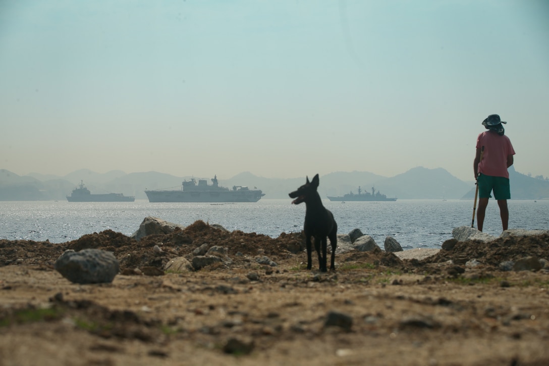 GUANABARA BAY (Sept. 10, 2022) A fisherman watches ships waiting to be reviewed by the President of Brazil Jair Bolsonaro during UNITAS LXIII, Sept. 10, 2022. UNITAS is the world’s longest-running maritime exercise. Hosted this year by Brazil, it brings together multinational forces from Belize, Brazil, Cameroon, Chile, Colombia, Dominican Republic, Ecuador, France, Guyana, Jamaica, Mexico, Namibia, Panama, Paraguay, Peru, South Korea, Spain, United Kingdom, Uruguay, and the United States conducting operations in and off the coast of Rio de Janeiro. The exercise trains forces to conduct joint maritime operations through the execution of anti-surface, anti-submarine, anti-air, amphibious and electronic warfare operations that enhance warfighting proficiency and increase interoperability among participating naval and marine forces. (U.S. Marine Corps photo by Cpl. Ethan Craw/Released)