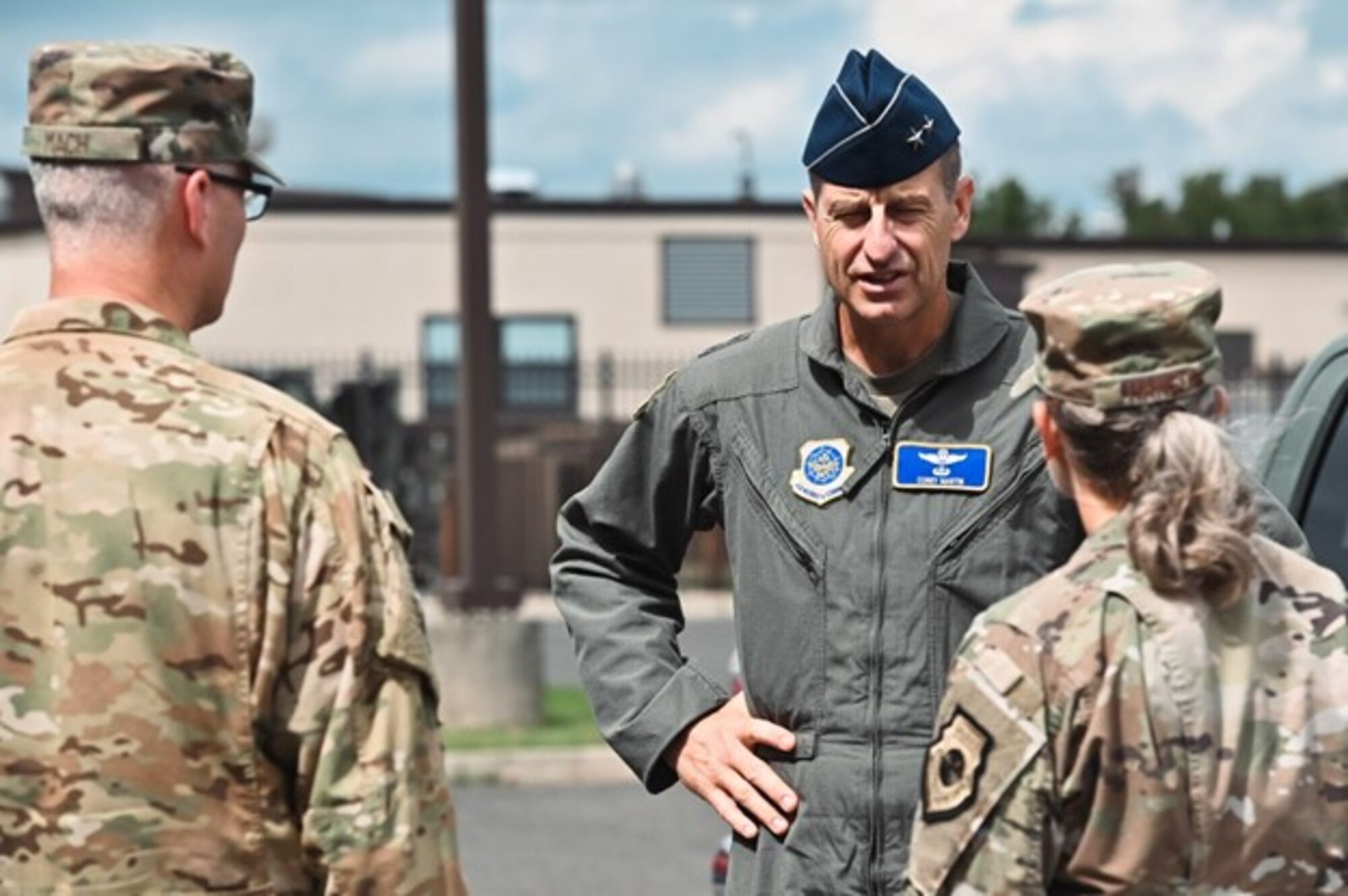 Maj. Gen. Corey Martin speaks to two airmen outside