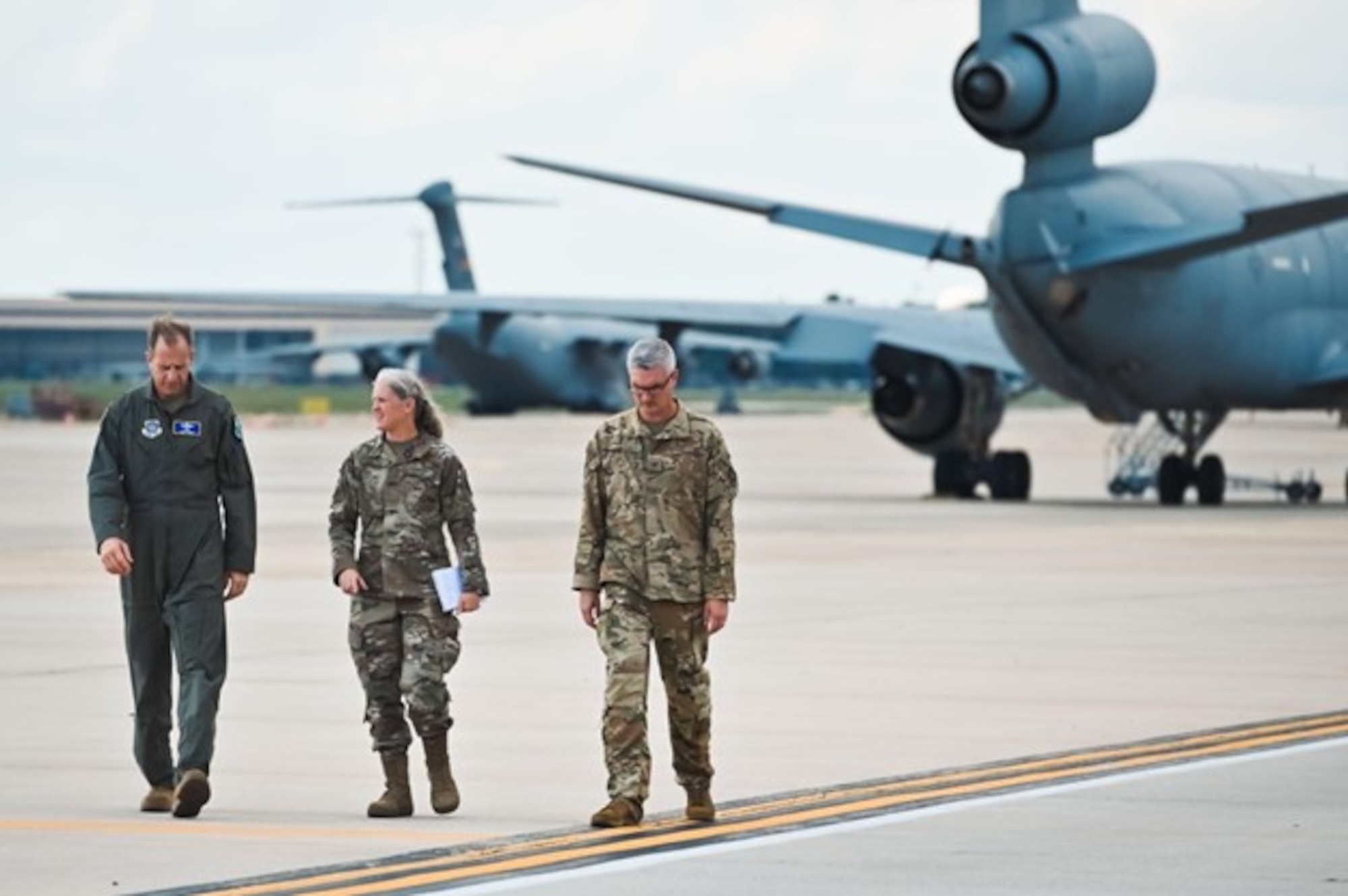 Three airmen walk down flight line