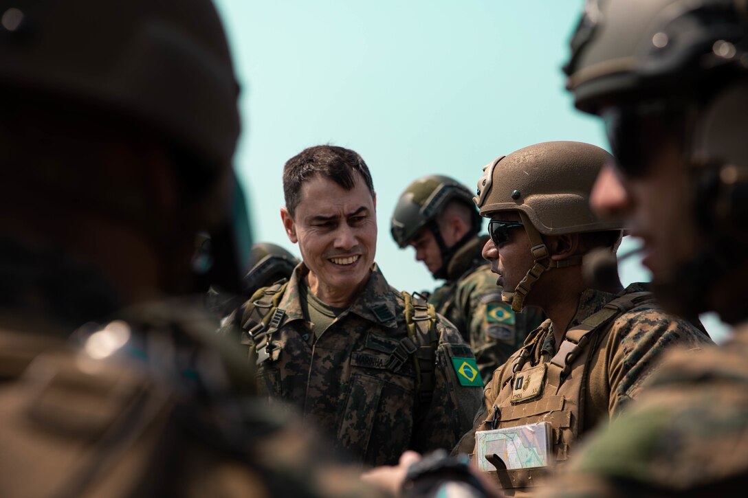 Capitao de mar e guerra Wagner Grund Marinho (Colonel Brazilian Marine Corps), left, commanding officer of Air Combat Team, Brazilian Marine Corps, and U.S. Marine Corps Capt. Aditya Atholi, platoon commander of 4th Air Naval Gunfire Liaison Company, Marine Forces Reserve, in support of Special Purpose Marine Air-Ground Task Force UNITAS LXIII, converse during close air support drills as part of exercise UNITAS LXIII at Santa Cruz Air Force Base, Rio de Janeiro, Sept. 8, 2022. Marine Light Attack Helicopter Squadron (HMLA) 773 and 4th ANGLICO cross trained with the Brazilian Marine Corps by conducting close air support drills, which consists of locating targets from the ground and relaying coordinates to assets in the sky to destroy. UNITAS trains forces to conduct joint maritime operations through the execution of anti-surface, anti-submarine, anti-air, amphibious and electronic warfare operations that enhance warfighting proficiency and increase interoperability among participating naval and marine forces. (U.S. Marine Corps photo by Cpl. Colton K. Garrett)