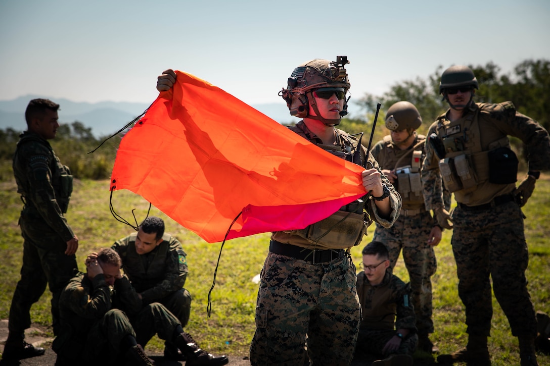 U.S. Marine Corps Sgt. Brian Wu, a joint terminal attack controller with 4th Air Naval Gunfire Liaison Company, Marine Forces Reserve, in support of Special Purpose Marine Air-Ground Task Force UNITAS LXIII, waves a flag to signal medical vehicles during a simulated casualty evacuation during exercise UNITAS LXIII, Santa Cruz Air Force Base, Rio de Janeiro,  Sept. 7, 2022. 4th ANGLICO and the Brazilian Marine Corps tested the capability of transporting wounded marines by Brazilian military medical units. UNITAS trains forces to conduct joint maritime operations through the execution of anti-surface, anti-submarine, anti-air, amphibious and electronic warfare operations that enhance warfighting proficiency and increase interoperability among participating naval and marine forces. (U.S. Marine Corps photo by Cpl. Colton K. Garrett)