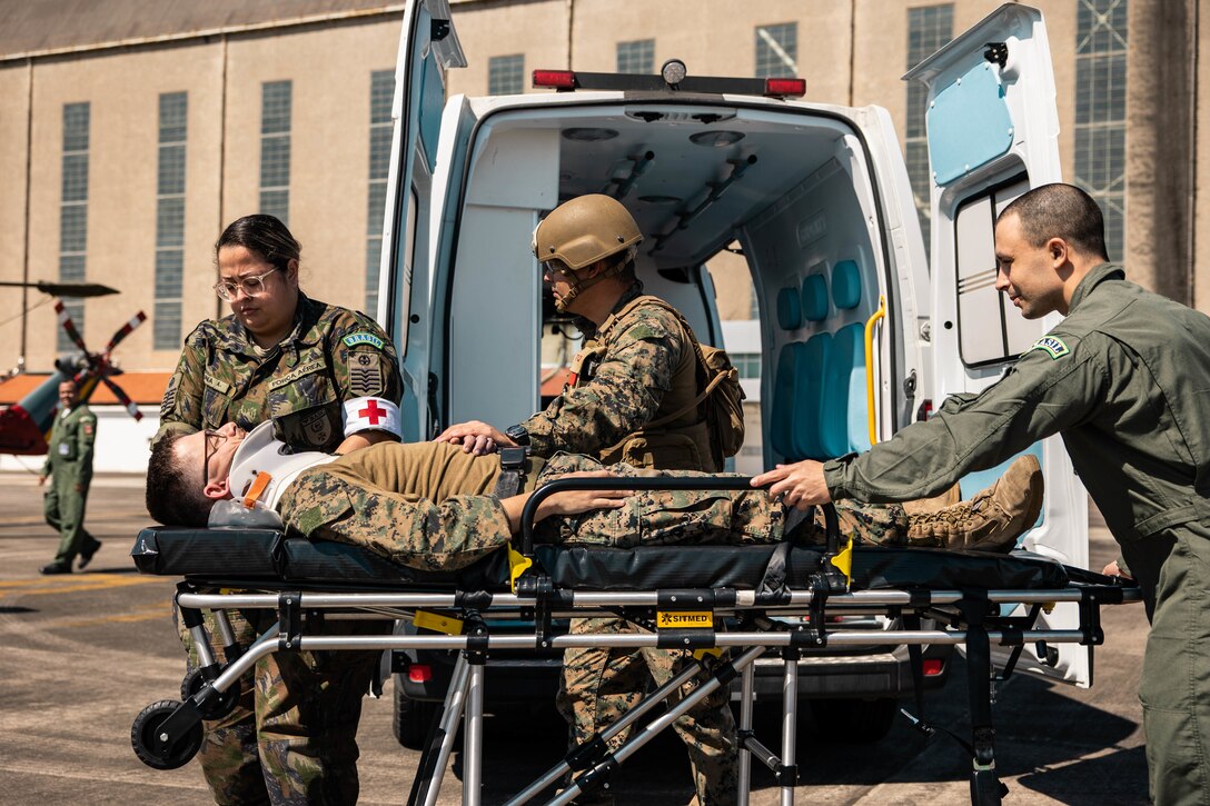 A U.S. Marine with 4th Air Naval Gunfire Liaison Company, Marine Forces Reserve, in support of Special Purpose Marine Air-Ground Task Force UNITAS LXIII and Brazilian Air Force medical staff push a marine on a gurney during a simulated casualty evacuation during exercise UNITAS LXIII, Santa Cruz Air Force Base, Rio de Janeiro, Sept. 7, 2022. 4th ANGLICO and the Brazilian Marine Corps tested the capability of transporting wounded Marines by Brazilian military medical units. UNITAS trains forces to conduct joint maritime operations through the execution of anti-surface, anti-submarine, anti-air, amphibious and electronic warfare operations that enhance warfighting proficiency and increase interoperability among participating naval and marine forces. (U.S. Marine Corps photo by Cpl. Colton K. Garrett)