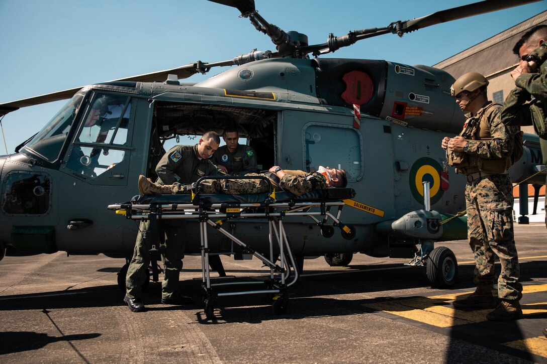 A U.S. Marine with 4th Air Naval Gunfire Liaison Company, Marine Forces Reserve, in support of Special Purpose Marine Air-Ground Task Force UNITAS LXIII, is prepped to enter a Brazilian Air Force medical helicopter during a simulated casualty evacuation during exercise UNITAS LXIII, Santa Cruz Air Force Base, Rio de Janeiro, Sept. 7, 2022. 4th ANGLICO and the Brazilian Marine Corps tested the capability of transporting wounded marines by Brazilian military medical units. UNITAS trains forces to conduct joint maritime operations through the execution of anti-surface, anti-submarine, anti-air, amphibious and electronic warfare operations that enhance warfighting proficiency and increase interoperability among participating naval and marine forces. (U.S. Marine Corps photo by Cpl. Colton K. Garrett)