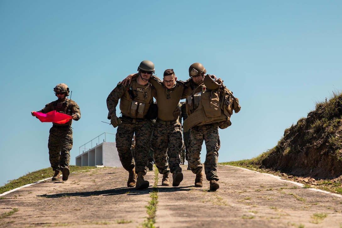 U.S. Marines with 4th Air Naval Gunfire Liaison Company, Marine Forces Reserve, in support of Special Purpose Marine Air-Ground Task Force UNITAS LXIII, assist a Marine down a ramp during a simulated casualty evacuation as part of exercise UNITAS LXIII, Santa Cruz Air Force Base, Rio de Janeiro, Sept. 7, 2022. 4th ANGLICO and the Brazilian Marine Corps tested the capability of transporting wounded marines by Brazilian military medical units. UNITAS trains forces to conduct joint maritime operations through the execution of anti-surface, anti-submarine, anti-air, amphibious and electronic warfare operations that enhance warfighting proficiency and increase interoperability among participating naval and marine forces. (U.S. Marine Corps photo by Cpl. Colton K. Garrett)