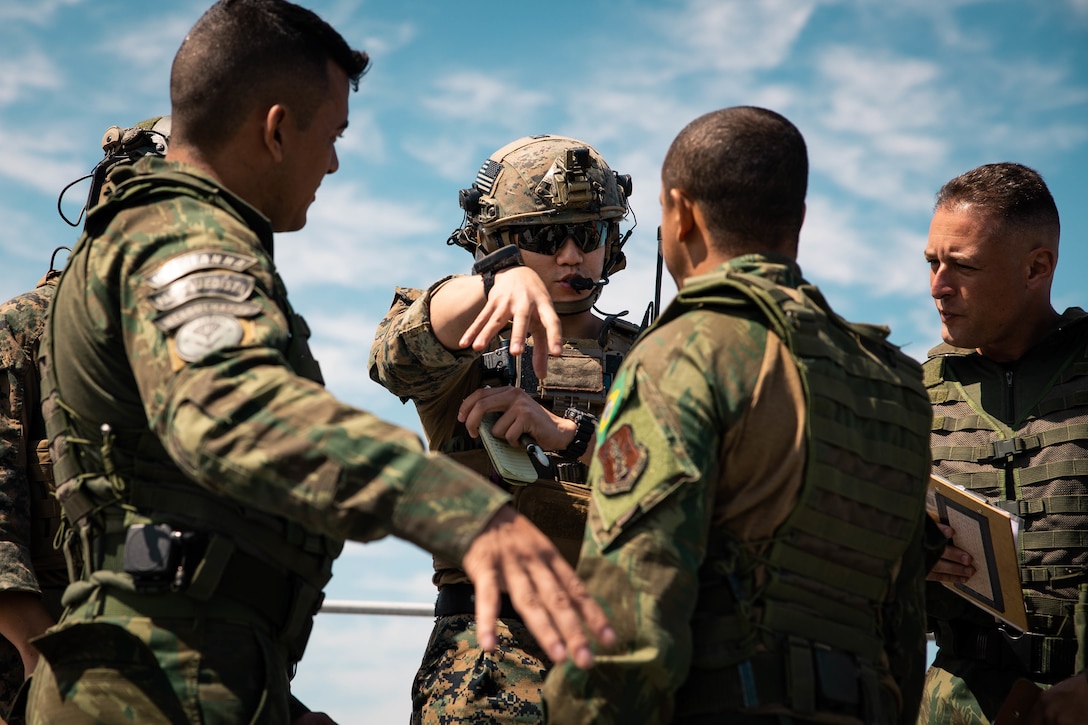 U.S. Marine Corps Sgt. Brian Wu, center, a joint terminal attack controller with 4th Air Naval Gunfire Liaison Company, Marine Forces Reserve, in support of Special Purpose Marine Air-Ground Task Force UNITAS LXIII, makes hand gestures to Brazilian marines during close air support drills as part of exercise UNITAS LXIII, Santa Cruz Air Force Base, Rio de Janeiro, Sept. 8, 2022. Light Attack Helicopter Squadron (HMLA) 773 and 4th ANGLICO cross trained with the Brazilian Marine Corps by conducting close air support drills, which consists of locating targets from the ground and relaying coordinates to assets in the sky to destroy. UNITAS trains forces to conduct joint maritime operations through the execution of anti-surface, anti-submarine, anti-air, amphibious and electronic warfare operations that enhance warfighting proficiency and increase interoperability among participating naval and marine forces. Wu is a native of Miami, FL. (U.S. Marine Corps photo by Cpl. Colton K. Garrett)