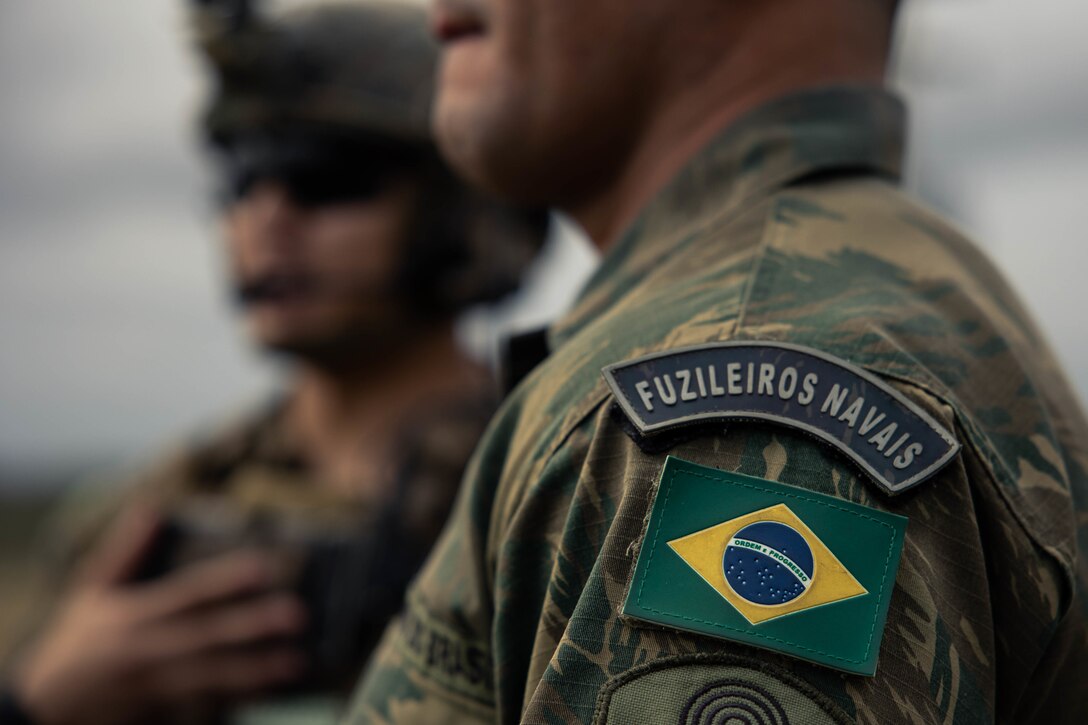The shoulder patch of Terceio-Sargento (Sergeant Brazilian Marine Corps) Igor Aleixo, a forward observer with the Brazilian Marine Corps, is seen during call for fire drills as part of exercise UNITAS LXIII at São Pedro da Aldeia, Brazil, Sept. 5, 2022. Marine Light Attack Helicopter Squadron (HMLA) 773 and 4th Air Naval Gunfire Liaison Company, Marine Forces Reserve, in support of Special Marine Air-Ground Task Force UNITAS LXIII, cross trained with the Brazilian Marine Corps by conducting simulated close air support drills, which consists of locating targets from the ground and relaying coordinates to assets in the sky to destroy. UNITAS trains forces to conduct joint maritime operations through the execution of anti-surface, anti-submarine, anti-air, amphibious and electronic warfare operations that enhance warfighting proficiency and increase interoperability among participating naval and marine forces. (U.S. Marine Corps photo by Cpl. Colton K. Garrett)