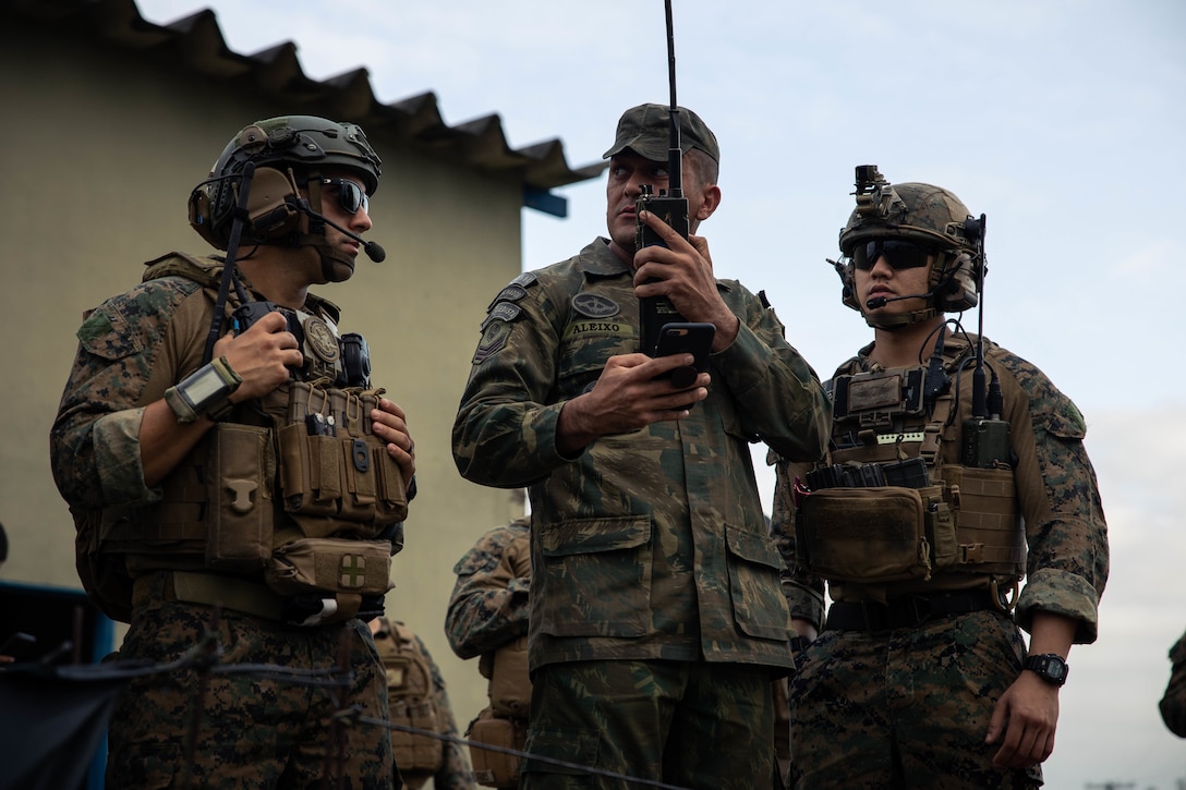 From left, U.S. Marine Corps Gunnery Sgt. Julio Arias, with 4th Air Naval Gunfire Liaison Company, Marine Forces Reserve, in support of Special Purpose Marine Air-Ground Task Force UNITAS LXIII, Terceio-Sargento (Sergeant Brazilian Marine Corps) Igor Aleixo, a forward observer with the Brazilian Marine Corps, and U.S Marine Corps Sgt. Brian Wu, with 4th ANGLICO, right, conduct call for fire drills at São Pedro da Aldeia, Brazil, Sept. 5, 2022. Marine Light Attack Helicopter Squadron (HMLA) 773 and 4th ANGLICO cross trained with the Brazilian Marine Corps by conducting simulated close air support drills, which consists of locating targets from the ground and relaying coordinates to assets in the sky to destroy. UNITAS trains forces to conduct joint maritime operations through the execution of anti-surface, anti-submarine, anti-air, amphibious and electronic warfare operations that enhance warfighting proficiency and increase interoperability among participating naval and marine forces. (U.S. Marine Corps photo by Cpl. Colton K. Garrett)