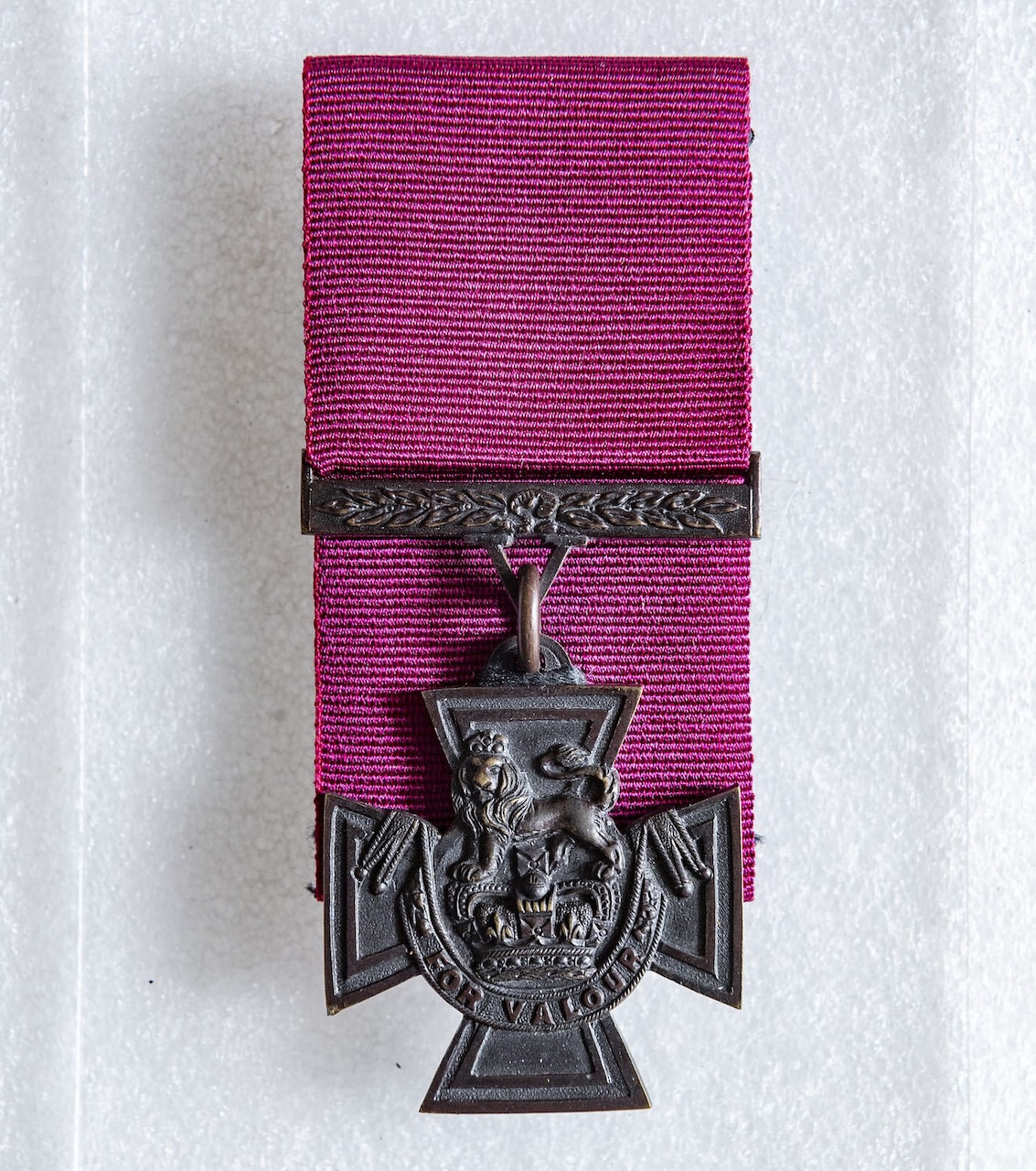 A medal is displayed on a purple ribbon.