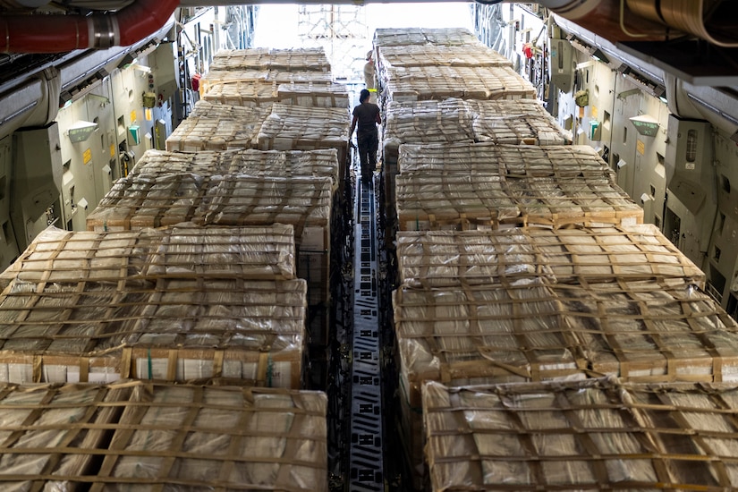 A person looks over pallets packed inside a cargo plane.
