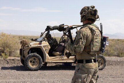 A Special Forces Soldier stands by a razor off-road vehicle.
