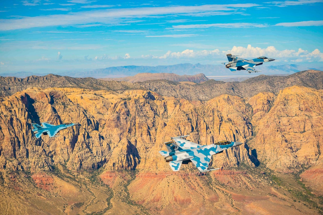 Three aircraft fly near mountains.