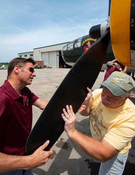 Dave Shiffer (left), Champaign Aviation Museum executive director and head of flight operations, and volunteer Matt Davis help cycle a prop on the World War II B-25 bomber Champaign Gal while preparing to start the engine July 15, 2022, outside the museum at Grimes Field in Urbana, Ohio. Each engine holds more than 45 gallons of oil, and some of it pools in the lower pistons when not in use. Cycling propellers distributes the oil, which prevents engine damage. (U.S. Air Force photo by R.J. Oriez)